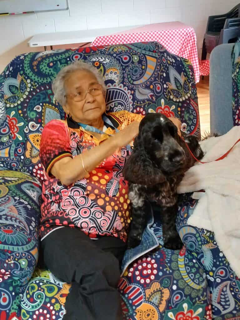 Elderly woman sitting with a black dog indoors