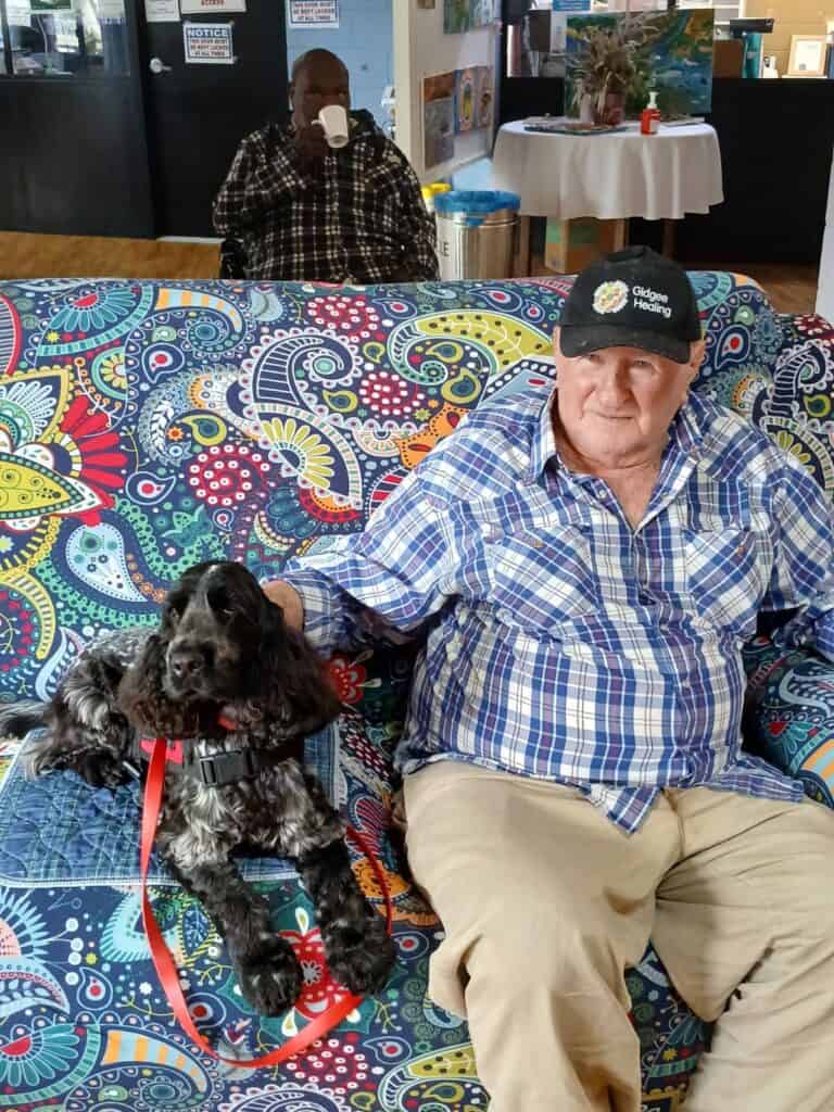 Man sitting with dog on colourful couch indoors